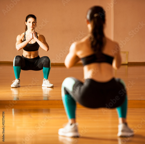 Beautiful fit woman making squats in gym