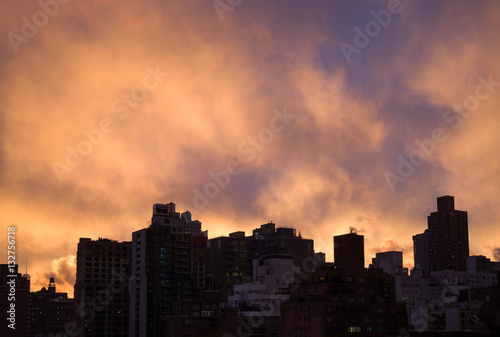 Dark silhouette tops of Manhattan cityscape, bright purple-orang