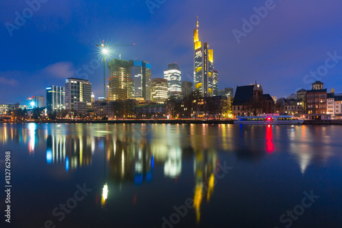 Picturesque view of business district with skyscrapers and mirror reflections in the river during morning blue hour, Frankfurt am Main, Germany