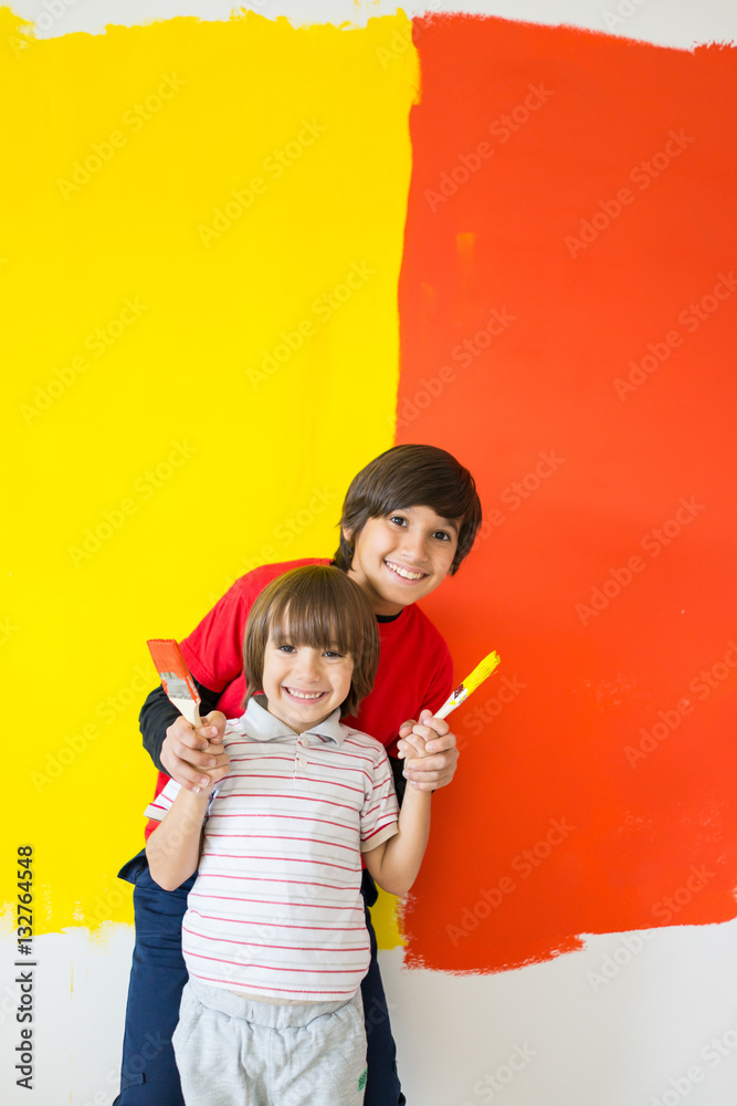 Adorable boy in bright paint with mess of paint child on wall Adorable boy in bright paint with mess of paint child on wall