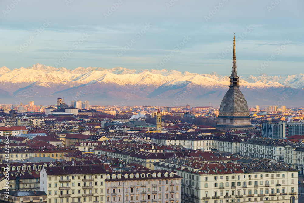 Torino (Turin, Italy): cityscape at sunrise with details of the Mole Antonelliana towering over the city. Scenic colorful light on the snowcapped Alps in the background.