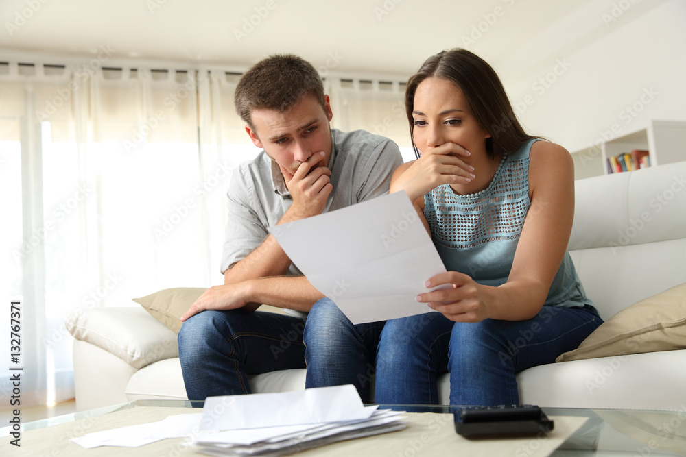 Worried couple reading a letter at home Worried couple reading a letter at home