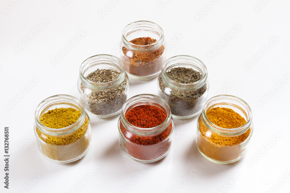 Spices in glass jars, turmeric, thyme, oregano, paprika, curry, for pilaf. Isolated on white. Spices in glass jars, turmeric, thyme, oregano, paprika, curry, for pilaf. Isolated on white.