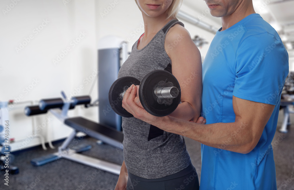 Personal trainer helping woman working with dumbbells at gym Personal trainer helping woman working with dumbbells at gym