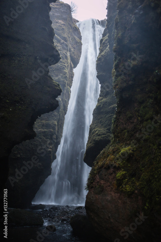 Iceland hidden waterfall in a cave in winter with spray