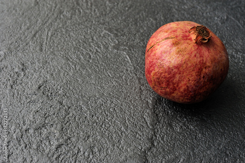 pomegranate on black background textured concrete surface