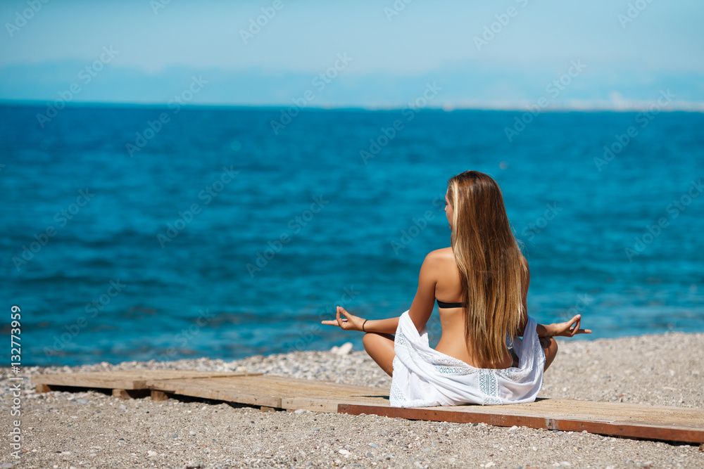 woman in lotus pose meditating at beach 