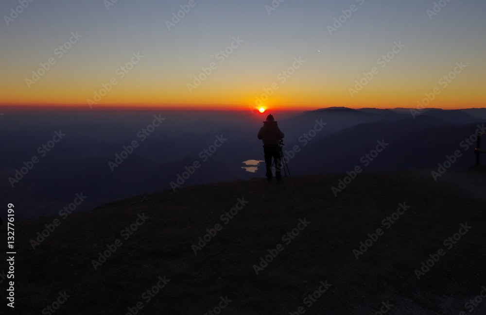 Photographer on the cliff above the lakes at sunset