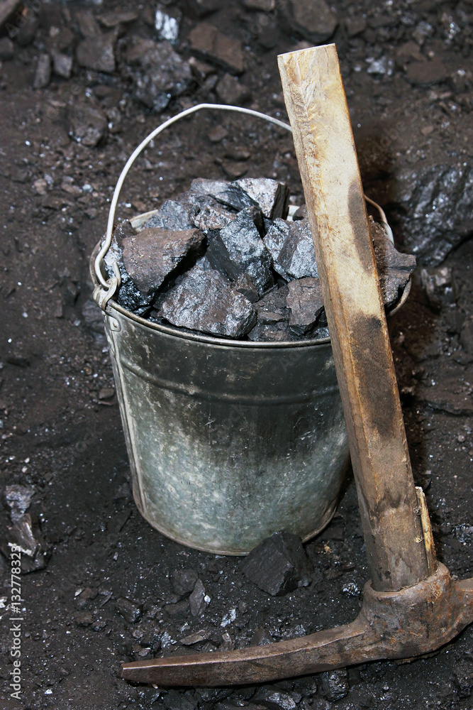 Coal mining. Pickaxe and the bucket with coal in mine Coal mining. Pickaxe and the bucket with coal in mine