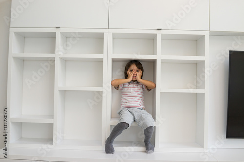 Child in shelf inside living room