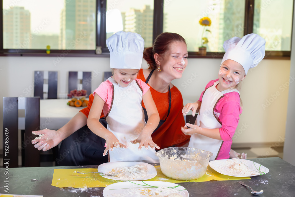 Two lovely children together with mother preparing a cake Two lovely children together with mother preparing a cake