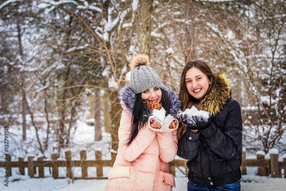 2 girls are holding snow and smiling