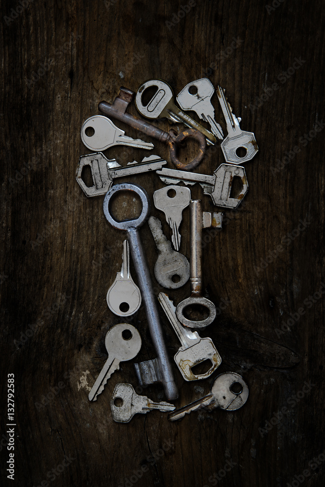 Various old keys in the shape of a keyhole on a dark rustic wooden board Various old keys in the shape of a keyhole on a dark rustic wooden board