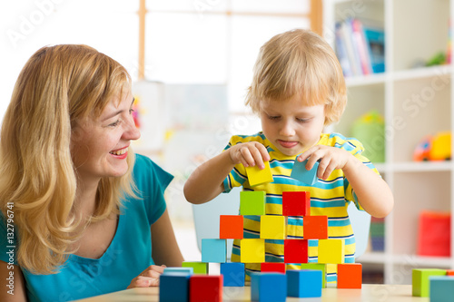 Child together with mom playing educational toys at home