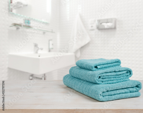 Turquoise spa towels pile on wood over blurred bathroom background