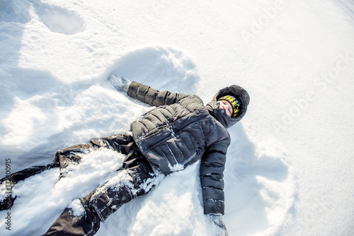 boy lying in the snow.