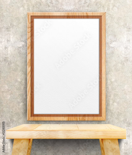 Blank wooden photo frame hanging at clean concrete wall on wood