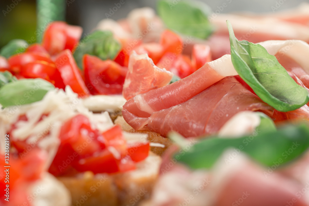Bruschetta with prosciutto, tomatoes, fresh basil close up Bruschetta with prosciutto, tomatoes, fresh basil close up