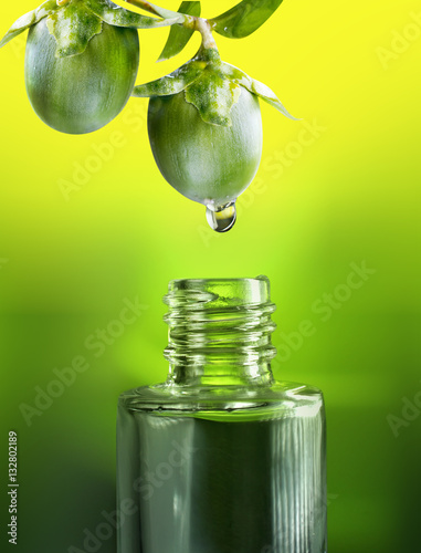 Photos Fruits and nuts  jojoba oil drop falls into the bottle vial close-up macro on a green and yellow background