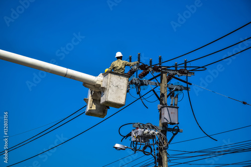Electrician perform maintenance on the transmission towers with use of claws- manholes and belt