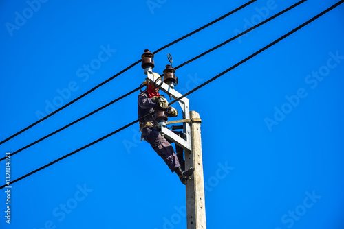 Electrician perform maintenance on the transmission towers with use of claws- manholes and belt