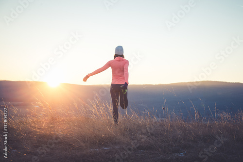Runner girl stretching on top of the hill