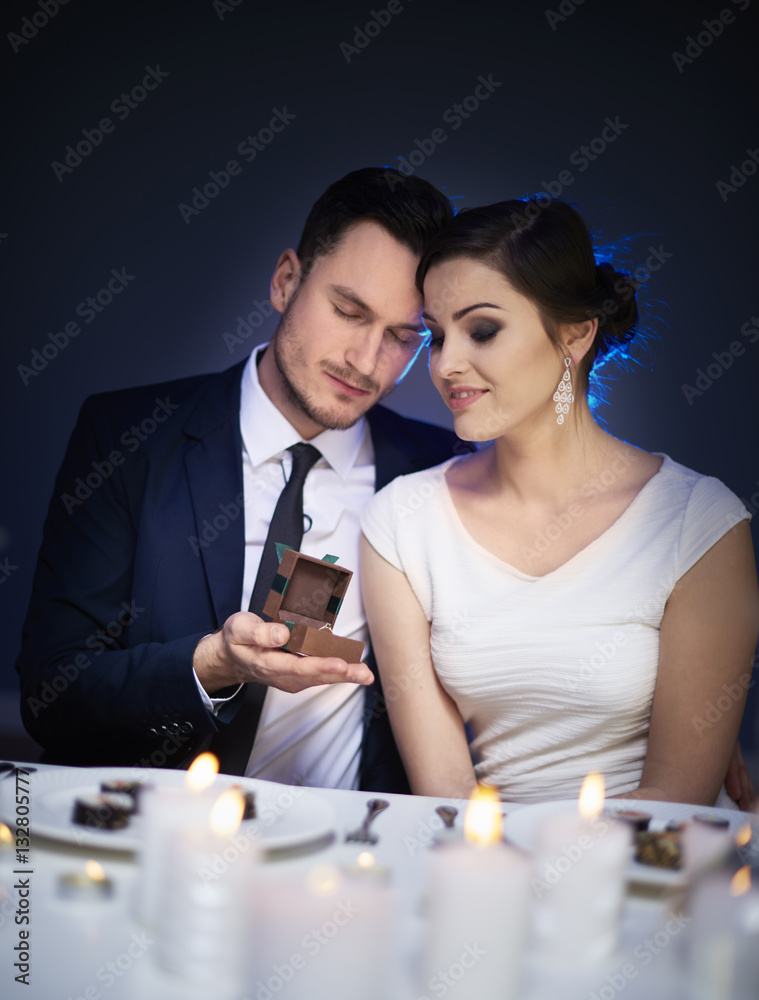 Man surprising woman with engagement ring at restaurant table Man surprising woman with engagement ring at restaurant table
