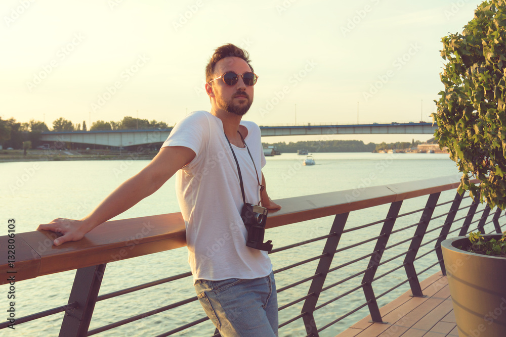 Guy posing outdoors with old camera.

