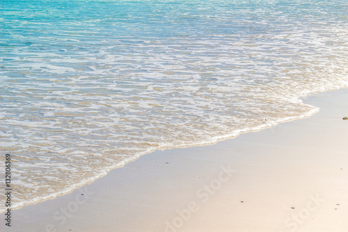 Soft wave of blue ocean on wet sandy beach. Background