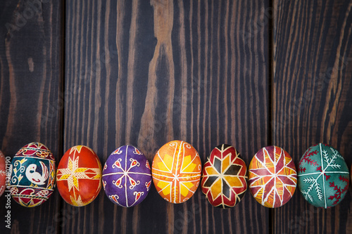Easter eggs in a row on dark wooden background.