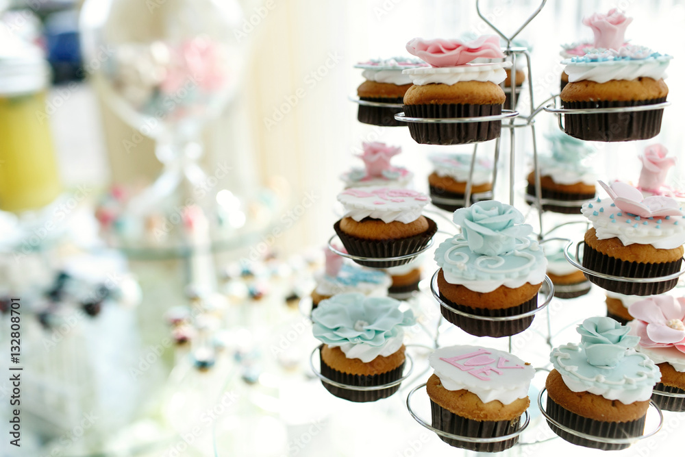 Tasty cupcakes with pink and blue glaze roses put in holders for