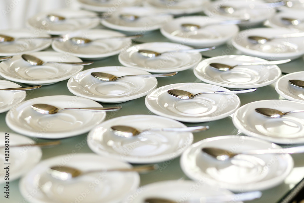 White plates of tea cups with silver spoons White plates of tea cups with silver spoons