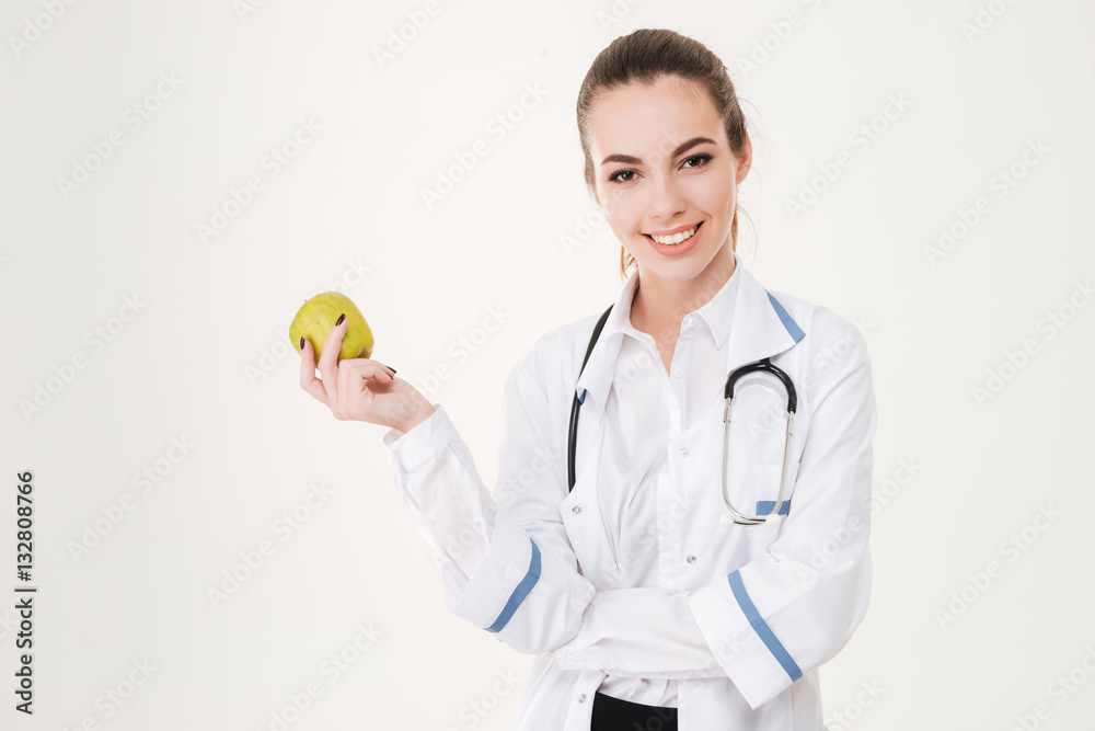 Happy young woman doctor smiling and holding an apple Happy young woman doctor smiling and holding an apple