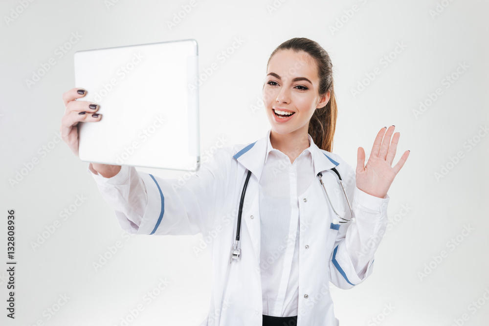 Smiling pretty young woman doctor having video confetence with tablet Smiling pretty young woman doctor having video confetence with tablet