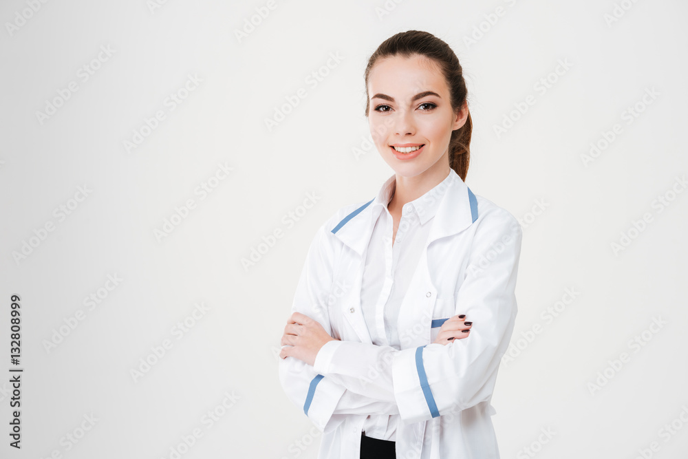 Happy beautiful young woman doctor standing with arms crossed Happy beautiful young woman doctor standing with arms crossed