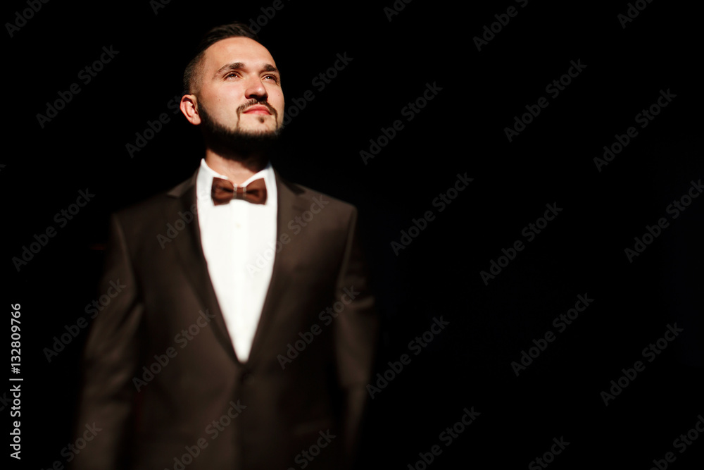 Bright face of handsome man in festive suit standing in the dark Bright face of handsome man in festive suit standing in the dark