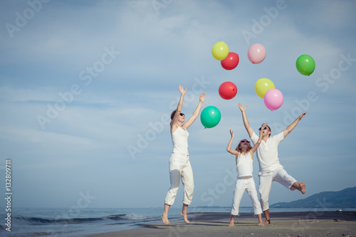 Happy family playing with balloons on the beach at the day time. © altanaka