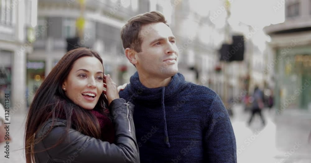 Attractive young woman pointing out something in an urban square to her smiling boyfriend or husband  close up head and shoulders