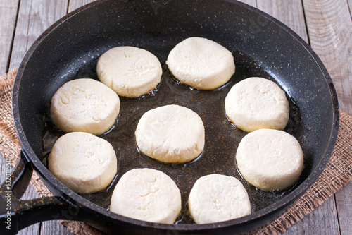 uncooked syrniki (Cottage cheese pancakes) in a frying pan