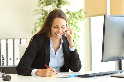 Businesswoman calling on phone and taking notes photo