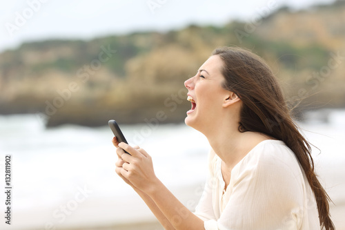 Foto Girl holding a smart phone crying desperately