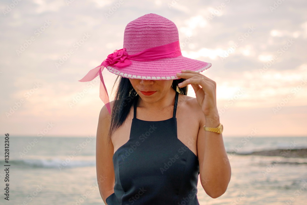 Model woman, black dress and straw hat on the beach