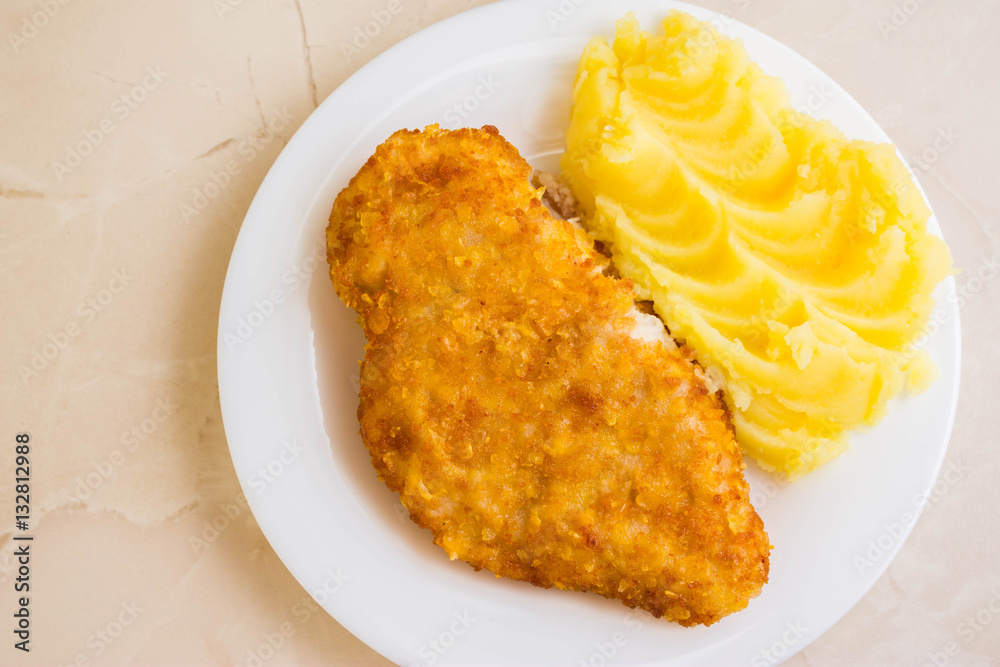 Chicken breast in breadcrumbs with mashed potatoes on a white plate Chicken breast in breadcrumbs with mashed potatoes on a white plate