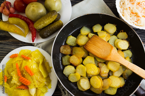 Fried potatoes in a pan with pickled vegetables