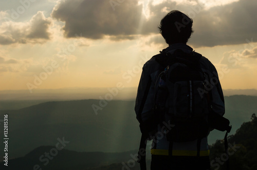 Silhouette man backpack standing on the top of the mountain looking a valley view at there are high mountains.