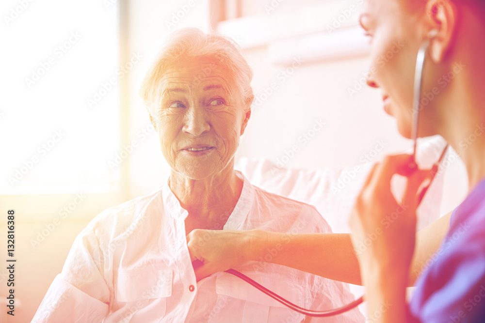 Fototapeta premium nurse with stethoscope and senior woman at clinic