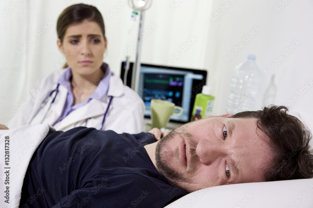 desperate ill man in hospital bed, almost crying for his healt condition. Doctor is sitting next to him desperate ill man in hospital bed, almost crying for his healt condition. Doctor is sitting next to him