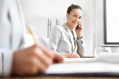 Doradca kredytowy. Bizneswoman rozmawia przez telefon siedząc przy biurku.