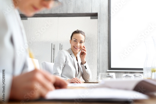 Bizneswoman rozmawia przez telefon siedząc przy biurku.