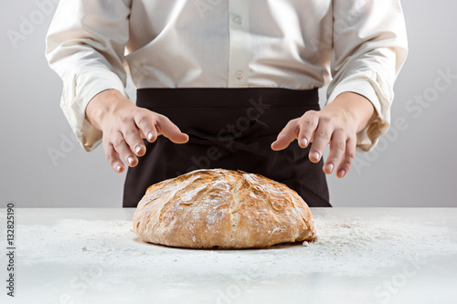 The male hands and rustic organic loaf of bread